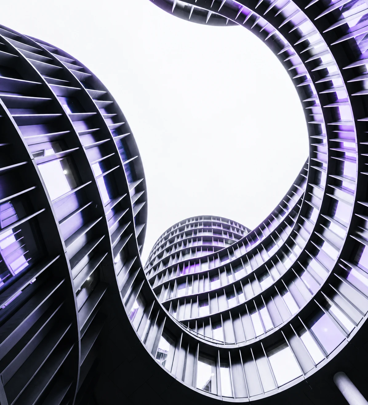 Curved architectural structures illuminated in violet, framing a clear open centre.